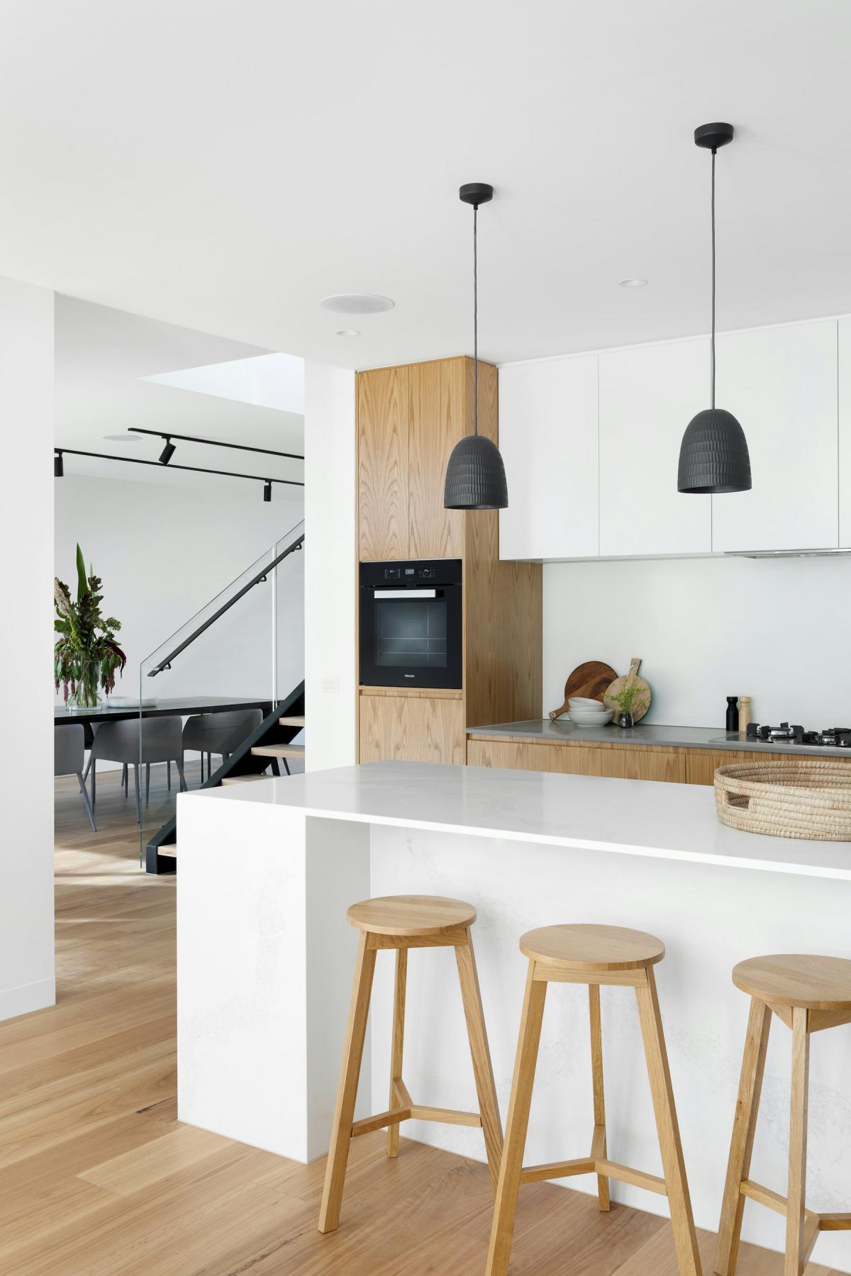 Contemporary Residence — Handleless modular kitchen with timber tall units and white counters